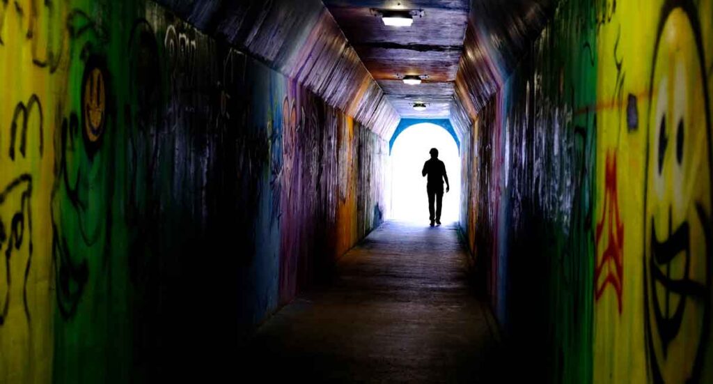 落書きだらけのトンネルを歩く男性